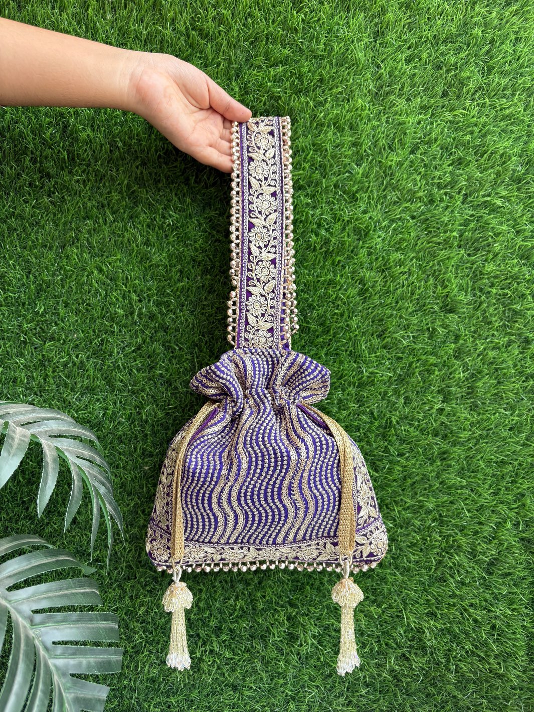 Decorative purple handbag with intricate patterns, unique tassels & handle
