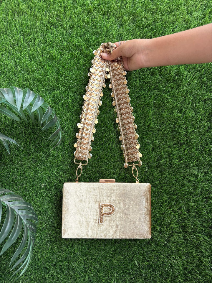Golden clutch bag featuring a statement sequin belt strap
