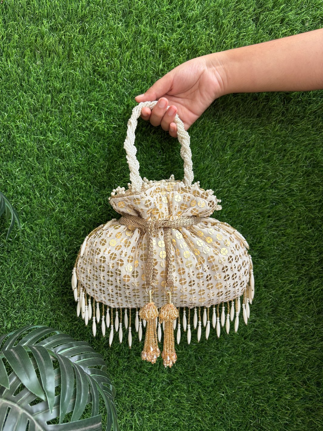 White potli bag with gold tassels and cascading pearl embellishments