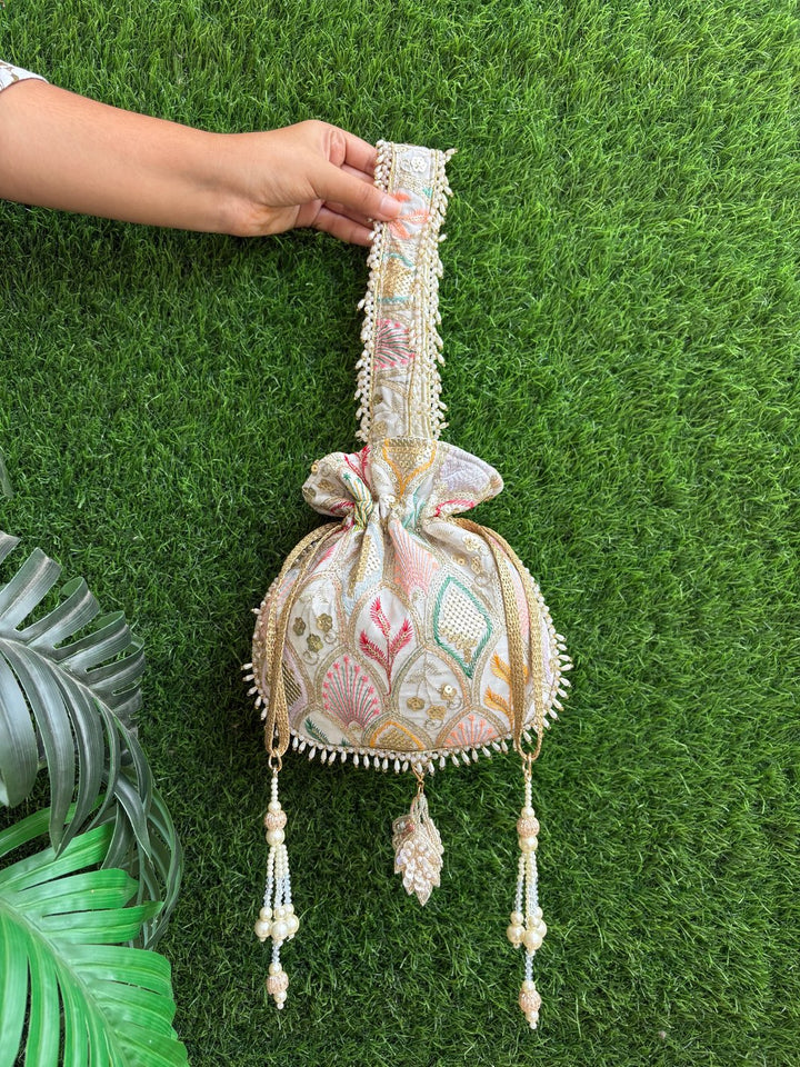 Decorative bag with intricate patterns held by a hand on a green grass background