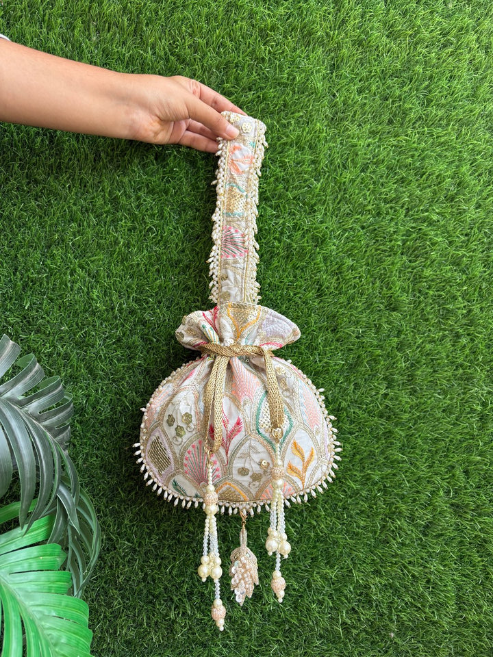 Decorative bag with floral patterns held by a hand on a green grass background