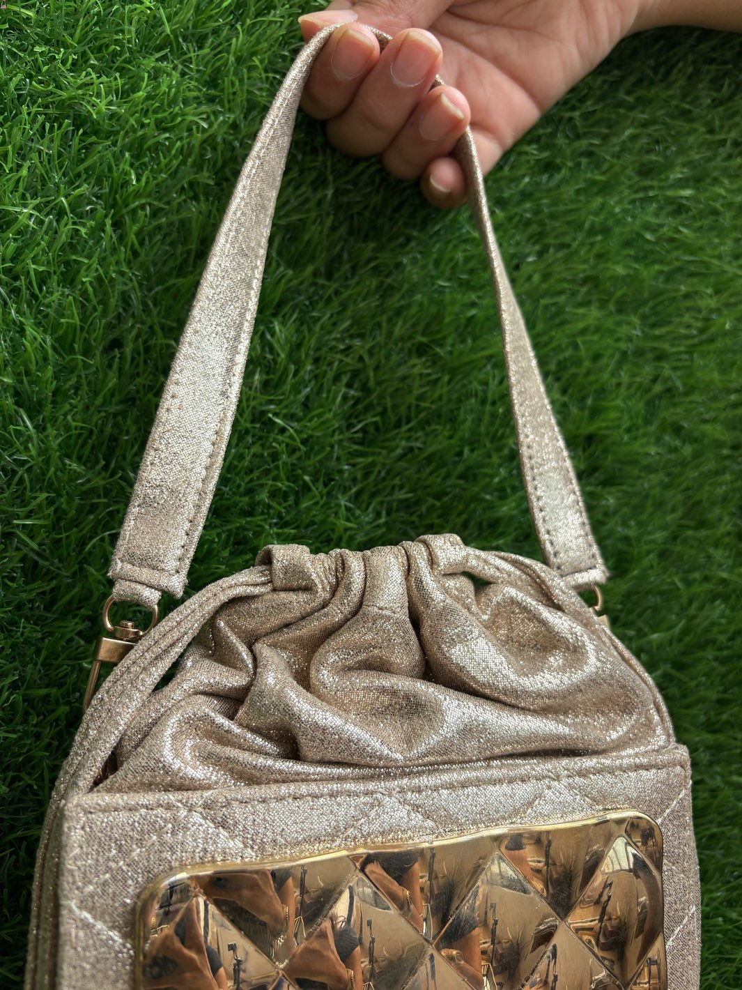Golden Metal Front Potli Clutch for Wedding shown in a close up view to check its intricate detailing