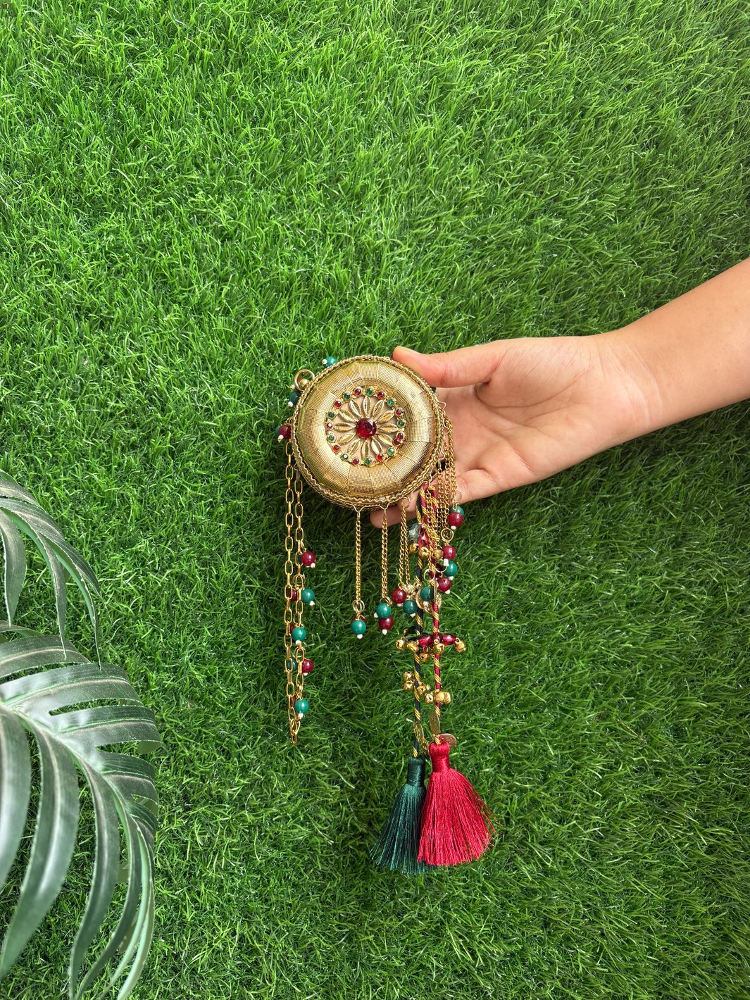 Mini gold metal clutch bag with contrasting green tassels