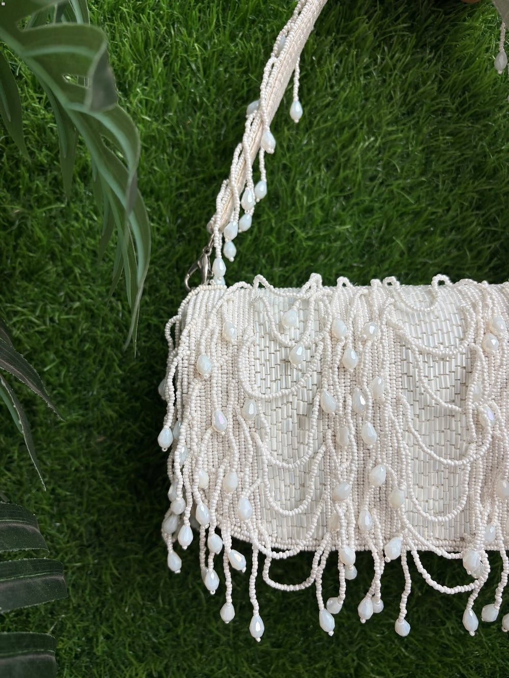 White crystal handbag with fringe details held against a green grass background perfect for every wedding to enhance your look - showcasing close up look