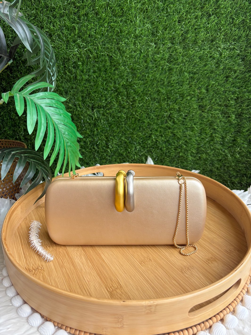 The Interlock Clutch champagne gold designer clutch with gold and silver statement handle